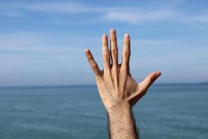 hand gör, visar siffra fem gest symbol på blå sommar himmel natur bakgrund. gestikulerar siffra 5. siffra fem i tecken språk. foto