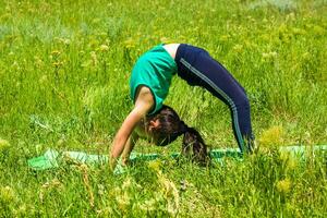 liten flicka i de fält, liten flicka håller på med yoga övningar i de parkera foto