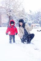 mor och de liten pojke är spelar i vinter- parkera, mor och söt pojke foto