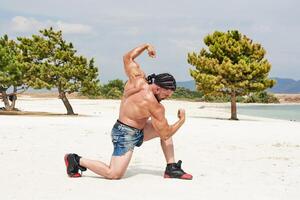 ung muskulös man utövar på de strand, ung muskulös man håller på med kroppsbyggnad övningar på de strand, atletisk ung man på de strand foto