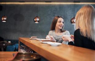 två vänner njuter av kaffe tillsammans på ett kafé när de sitter vid ett bord och chattar foto