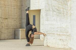 ung flicka håller på med övning i de stad, kvinna håller på med yoga träning, person håller på med stretching, kvinna avkopplande i de stad, Söt flicka håller på med kondition övning foto