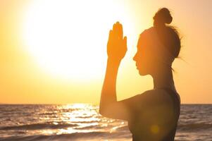 Lycklig kvinna silhuett, höjer henne händer till de Sol på gryning. frihet och andlighet begrepp foto
