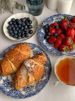 frukost med kaffe, croissanter och färsk bär på tabell foto