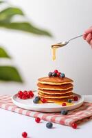 pannkakor med bär och lönn sirap på en vit bakgrund. foto