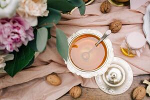 kopp av te med honung och valnötter på en trä- bakgrund foto