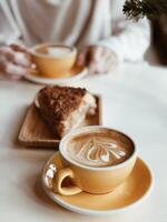 kaffe kopp med croissant och kvinna händer på tabell foto