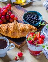 frukost med kaffe, croissant och bär på trä- styrelse foto