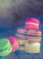 färgrik macarons på de trä- bakgrund foto