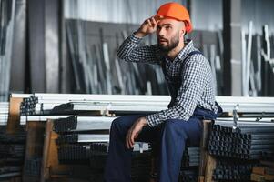 porträtt av professionell tung industri ingenjör arbetstagare bär säkerhet enhetlig, hård hatt leende. i de bakgrund ofokuserad stor industriell fabrik. foto