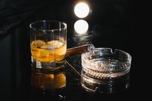 glas av kall whisky med cigarr på mörk bakgrund foto