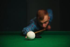 ung stilig man lutande över de tabell medan spelar snooker foto