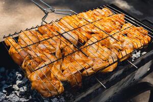 utsökt kyckling fräsning på utegrill grill galler utomhus. krydda faller på färsk grillad kyckling vingar. sommar fest mat idéer. bbq saftig rostning kyckling grill ben på grill galler foto