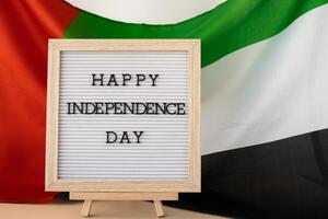 Lycklig oberoende dag text ram på förenad arab emirates vinka flagga tillverkad från silke material. åminnelse dag muslim offentlig Semester firande bakgrund. de nationell flagga av uae. patriotism foto