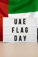 ljuslåda med text uae flagga dag på förenad arab emirates vinka flagga tillverkad från silke material. oberoende åminnelse dag muslim offentlig Semester firande bakgrund. de nationell flagga av uae. patriotism foto