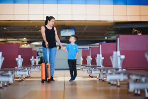 familj på flygplats innan flyg. mor och son väntar till styrelse på avresa Port av modern internationell terminal. reser och flygande med barn. mamma med unge ombordstigning flygplan. gul familj foto