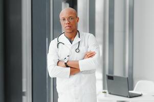 afrikansk amerikan man manlig sjukhus läkare i vit täcka med stetoskop. foto