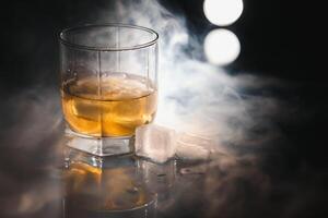 whisky med is på svart bakgrund med rök foto