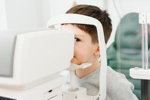 optometri begrepp. kvinna optiker optiker läkare undersöker syn av barn pojke i öga oftalmologiska klinik. foto