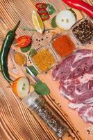 rå fläsk kött med kryddor och grönsaker på trä- tabell. foto