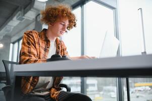 glad manlig frilansare bläddring rolig video innehåll medan nätverkande i social media använder sig av netbook teknologi i gata Kafé, Lycklig hipster kille njuter fri tid för uppkopplad bloggande via bärbar dator foto