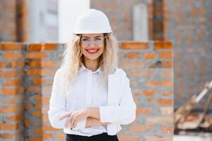 konstruktion ingenjör. flicka med konstruktion dokumentation. en kvinna i en vit hård hatt mot de tak av en byggnad. konstruktion av en ny hus. foto