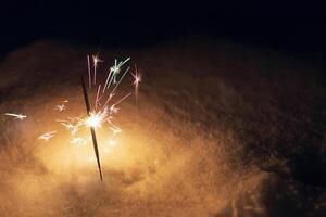 festlig sparklers bränna på de snö på natt. ny år och jul kort foto