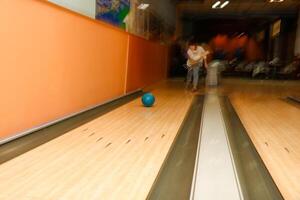 senior kvinna i rörelse och fläck kastar boll i bowling klubb foto