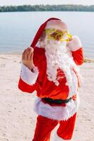 santa claus i rolig glasögon på de sjö strand. resa och semester begrepp foto