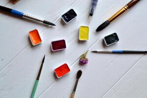 verktyg för målning på de vit trä- skrivbord. borstar och målarfärger på de tabell. målares arbetsplats. foto