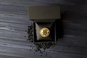 gyllene bitcoin i en svart låda. guld mynt av kryptovaluta. foto