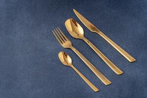 uppsättning av bestick tillverkad av guld metall. gaffel, sked, kniv, tesked. foto