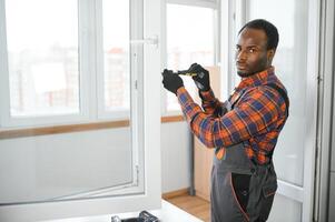 en afrikansk reparatör reparationer, justerar eller installerar metall-plast fönster i de lägenhet foto