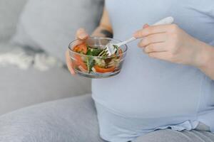 skön friska gravid kvinna äter vegetabiliska sallad foto