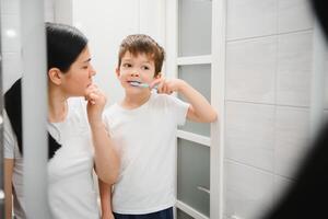 skön mor och Lycklig son pensling tänder nära spegel i badrum foto