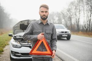 ledsen man nära bruten bil sökande hjälp i fält foto