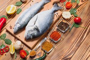 rå fisk matlagning och Ingredienser. dorado, citron, örter och kryddor. topp se med kopia Plats på tabell foto