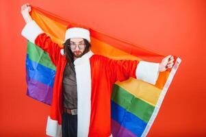 Gay man klädd som santa claus innehav en flerfärgad flagga foto