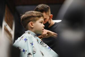 glad caucasian pojke få frisyr i frisör foto