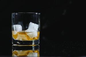 whisky glas svart bakgrund skinande foto