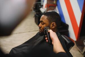besöker frisör. afrikansk amerikan man i en eleganta barberare affär foto