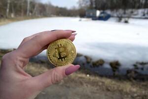 gyllene bitcoin i kvinna hand. en mynt av kryptovaluta. foto