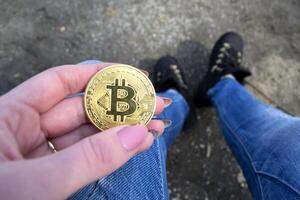 gyllene bitcoin i kvinna hand. en mynt av kryptovaluta. foto