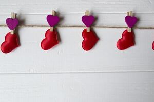 röd kärlek hjärtan fäst på en dekorativ klädnypa. foto