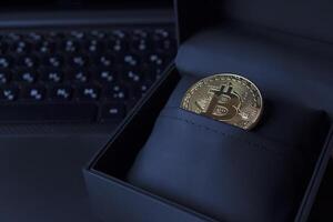 gyllene bitcoin i svart låda på de bärbar dator tangentbord. foto