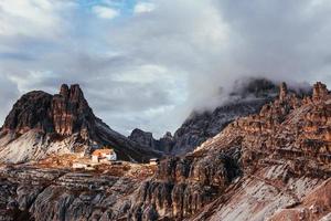 solljuset kommer knappt genom de tjocka molnen. turistiska byggnader som väntar på de människor som vill går genom dessa fantastiska dolomitberg foto