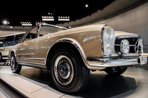 stuttgart, Tyskland - 16 oktober 2018 mercedes museum. buss i bakgrunden. brun bil från retrokollektion parkerad inomhus på bilmässan foto