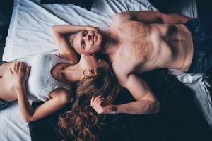 ett porträtt av ett lyckligt ungt par som kopplar av i en mysig säng foto