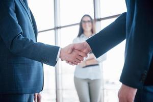 två självsäkra affärsmän skakar hand under ett möte på kontoret, hälsning och partner koncept