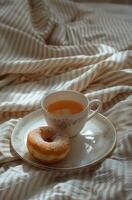ai genererad en kopp av te och en munk är visad på en säng till visa de frukost se foto